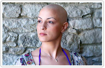 A woman in treatment standing against a stone wall